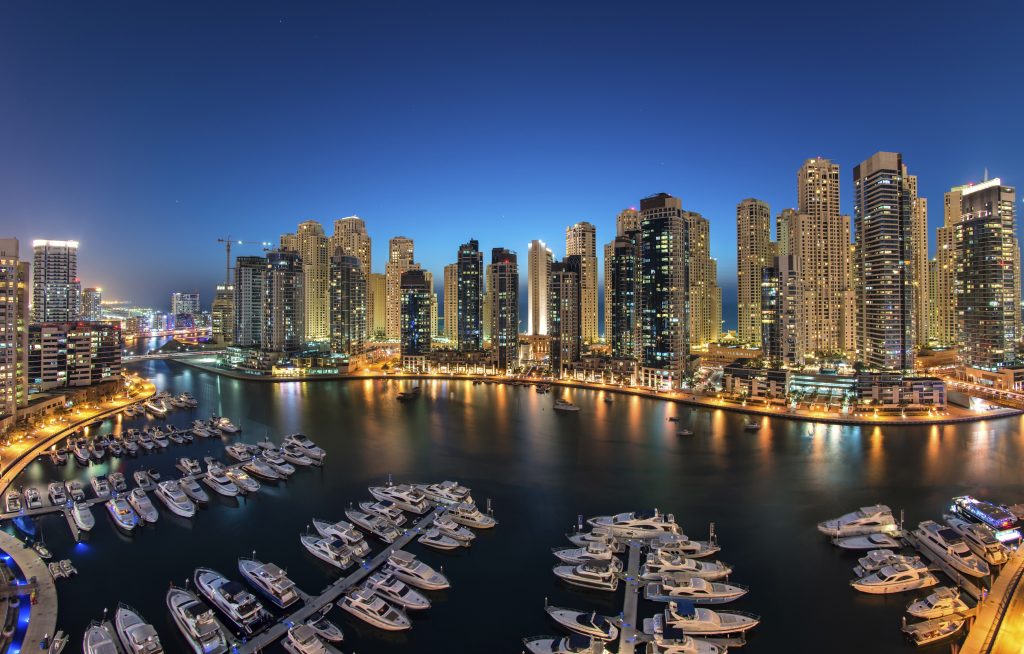 Cityscape of Dubai, United Arab Emirates at dusk, with skyscrapers and the marina in the foreground.