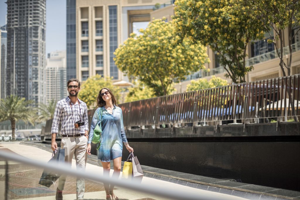 Couple strolling on walkway carrying shopping bags, Dubai, United Arab Emirates