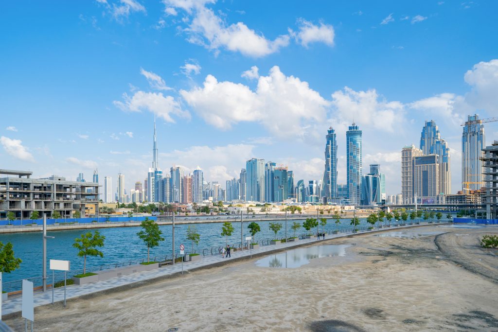 Burj Khalifa with lake or river and bridge in Dubai Downtown skyline, United Arab Emirates or UAE. Financial district and business area in urban city. Skyscraper buildings with blue sky. Reflection.