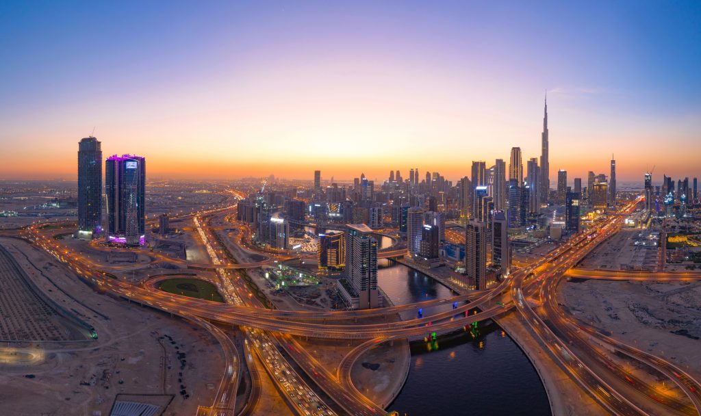 Aerial view of Burj Khalifa in Dubai Downtown skyline and highway, United Arab Emirates or UAE. Financial district and business area in smart urban city. Skyscraper and high-rise buildings at night.